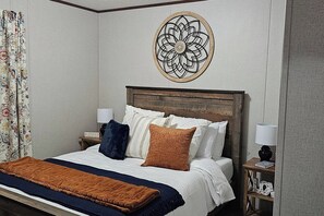 A neatly made bed with a headboard, a decorative wall piece, and a nightstand with a lamp.