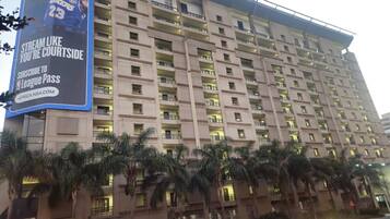 Un hotel de varios pisos con balcones y un gran cartel publicitario que anuncia la transmisión de la NBA.