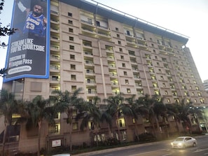 Un hotel de varios pisos con balcones y un gran cartel publicitario que anuncia la transmisión de la NBA.