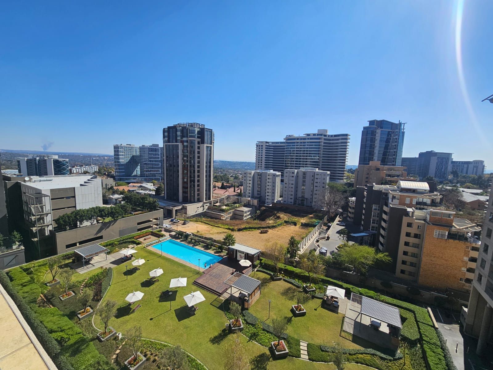 Un edificio residencial de gran altura con piscina en la azotea y jardín ajardinado.