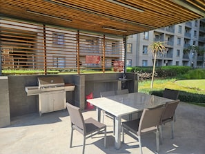 An outdoor patio with a grill, seating area, and a view of a residential building. - Sandton Westpoint Luxury Apartments - 7 (Sandton)