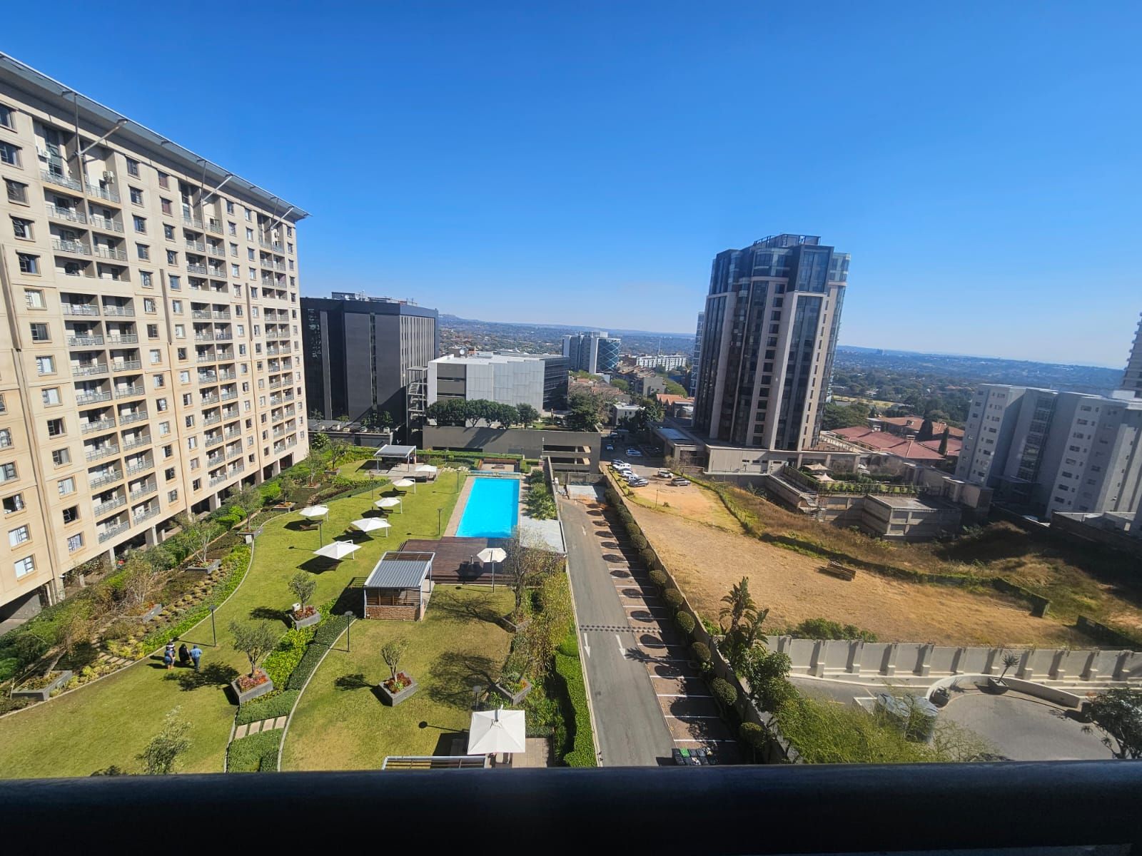 Un edificio residencial alto con piscina, zonas verdes y una vista despejada del paisaje urbano.