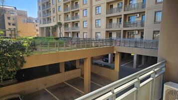 Una estructura de estacionamiento de varios pisos con un puente peatonal, rodeada de edificios con balcones.