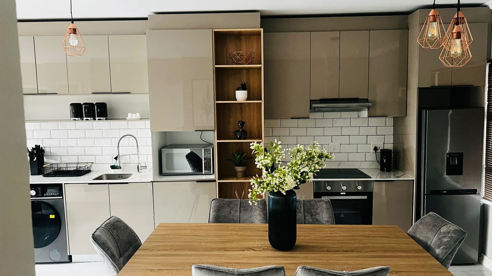 Una cocina moderna con electrodomésticos integrados, una mesa de comedor y un florero con flores.