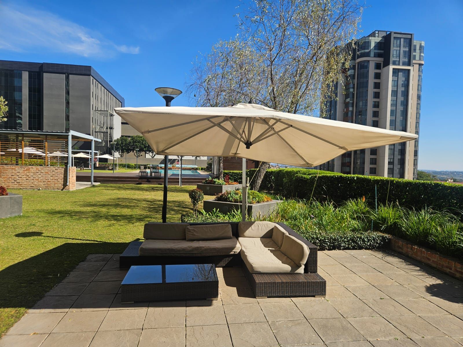 Un espacio al aire libre con un gran paraguas, un sofá y una mesa de centro.
