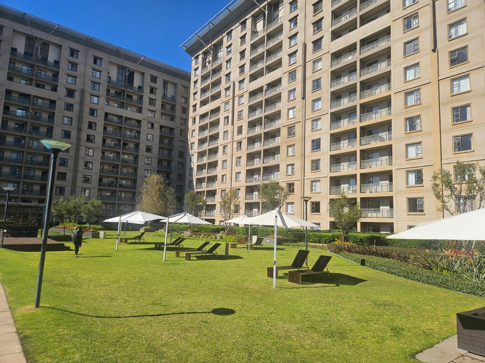 Un patio con mesas y sillas al aire libre, rodeado de edificios residenciales altos.
