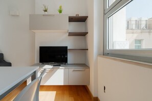 A modern kitchen with a flat-screen TV, built-in shelves, and a window with a view of buildings. - GuestHost - Cozy Central Apartment in Milan (Milan)