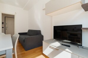 Una sala de estar moderna con un televisor de pantalla plana, un sofá gris, un mueble blanco y piso de madera.