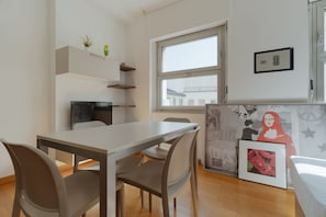 A modern dining area with a table and chairs, a window with a view, and a wall with artwork. - GuestHost - Cozy Central Apartment in Milan (Milan)