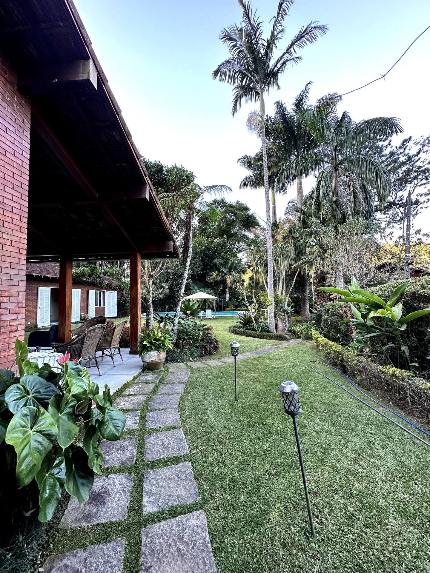Um jardim bem cuidado com um caminho de pedra que leva a uma área coberta com assentos.