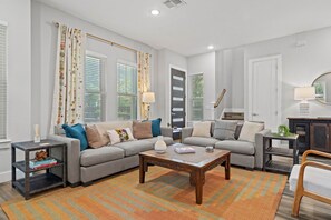 A living room with a sectional sofa, a coffee table, and a side table with books. - East Austin Twin-Home Retreat w/ Kids` Play Area & String-Lit Courtyard (Austin)