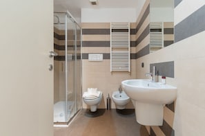 Ein modernes Badezimmer mit Duschkabine aus Glas, Toilette, Bidet und Waschbecken.