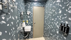 A bathroom with a sink, mirror, towel dispenser, and a door.
