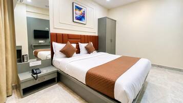 Una habitación de hotel con cama, mesita de noche, lámpara y televisor.