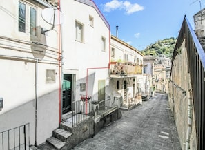 Una calle estrecha flanqueada por edificios, una escalera que conduce a una puerta y un cielo despejado.