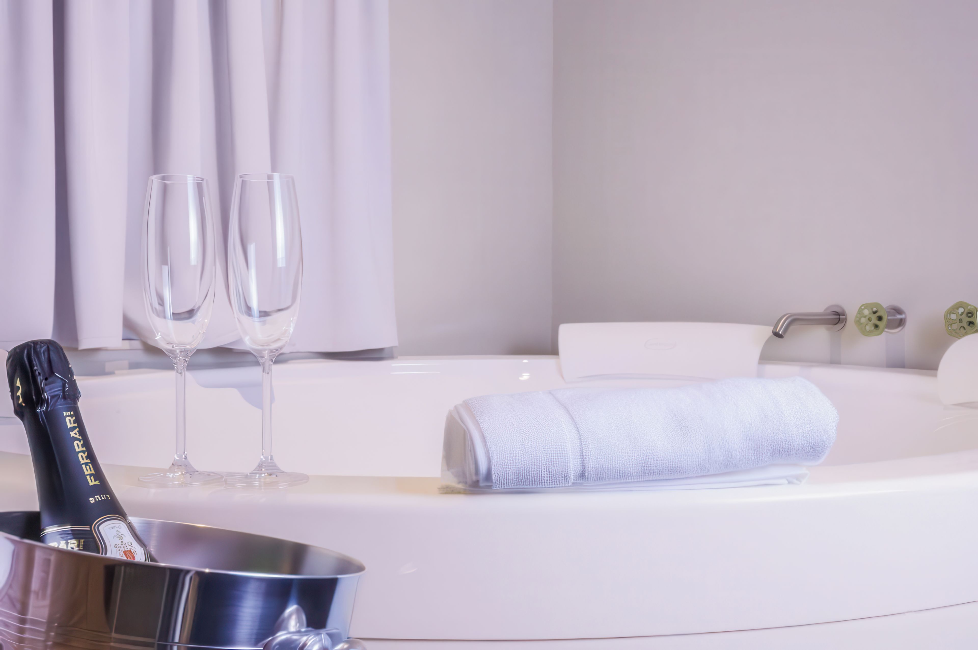 Een hotelkamer met een badkuip, een handdoek en twee champagneglazen.