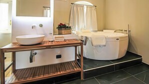 Un baño con tocador de madera, un espejo grande, una bañera independiente y una cortina de ducha.