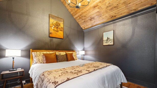 Een slaapkamer met een bed, twee bedlampen, een nachtkastje en een kroonluchter.
