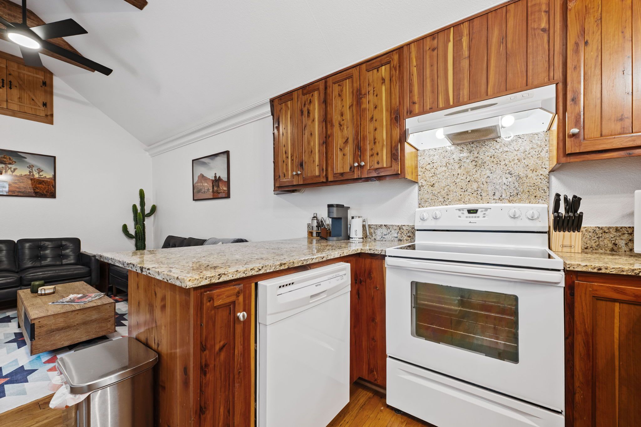 A kitchen with wooden cabinets, a built-in dishwasher, a stove, and granite countertops.