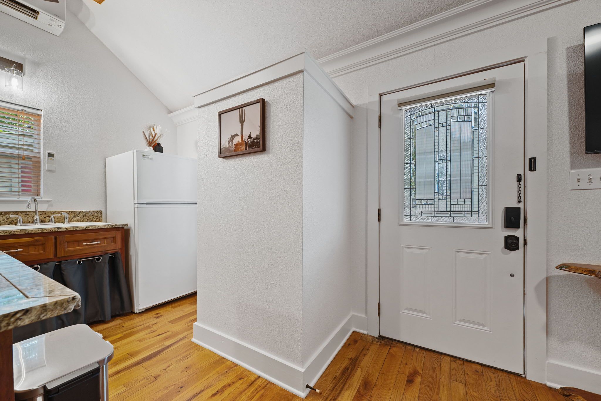 A kitchen with a refrigerator, a sink, and a window with blinds.