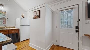 A kitchen with a refrigerator, a sink, and a window with blinds.
