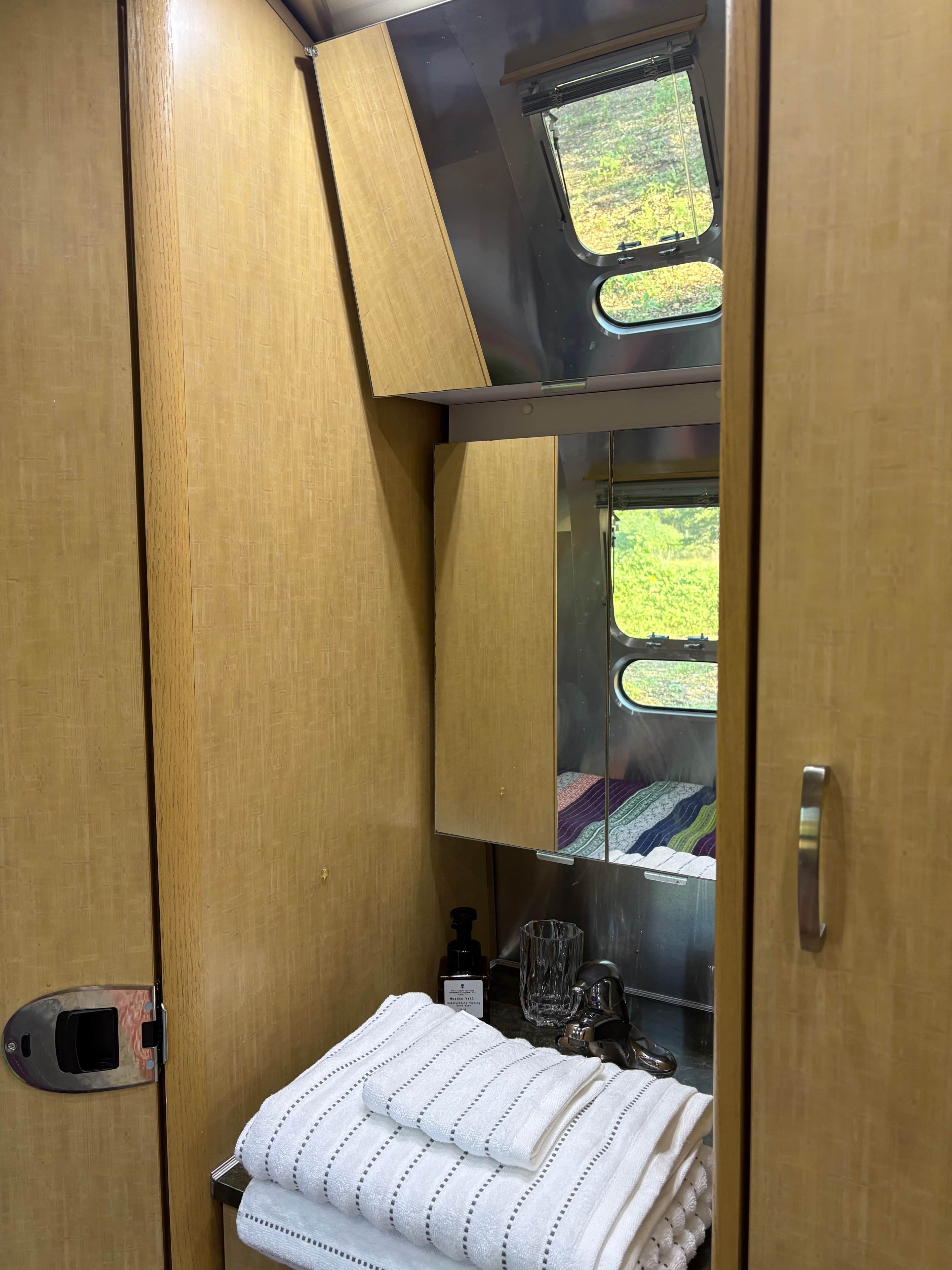 Une petite salle de bain avec un meuble-lavabo en bois, un miroir et une petite fenêtre.