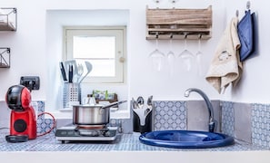 Una cucina con piano cottura a gas, una macchina da caffè, un lavello e una finestra.