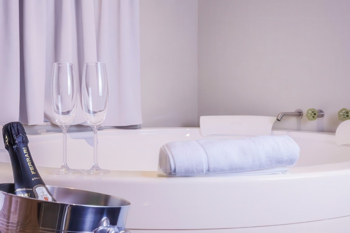 Une salle de bain moderne avec une baignoire, deux verres vides et une bouteille de champagne dans un seau.