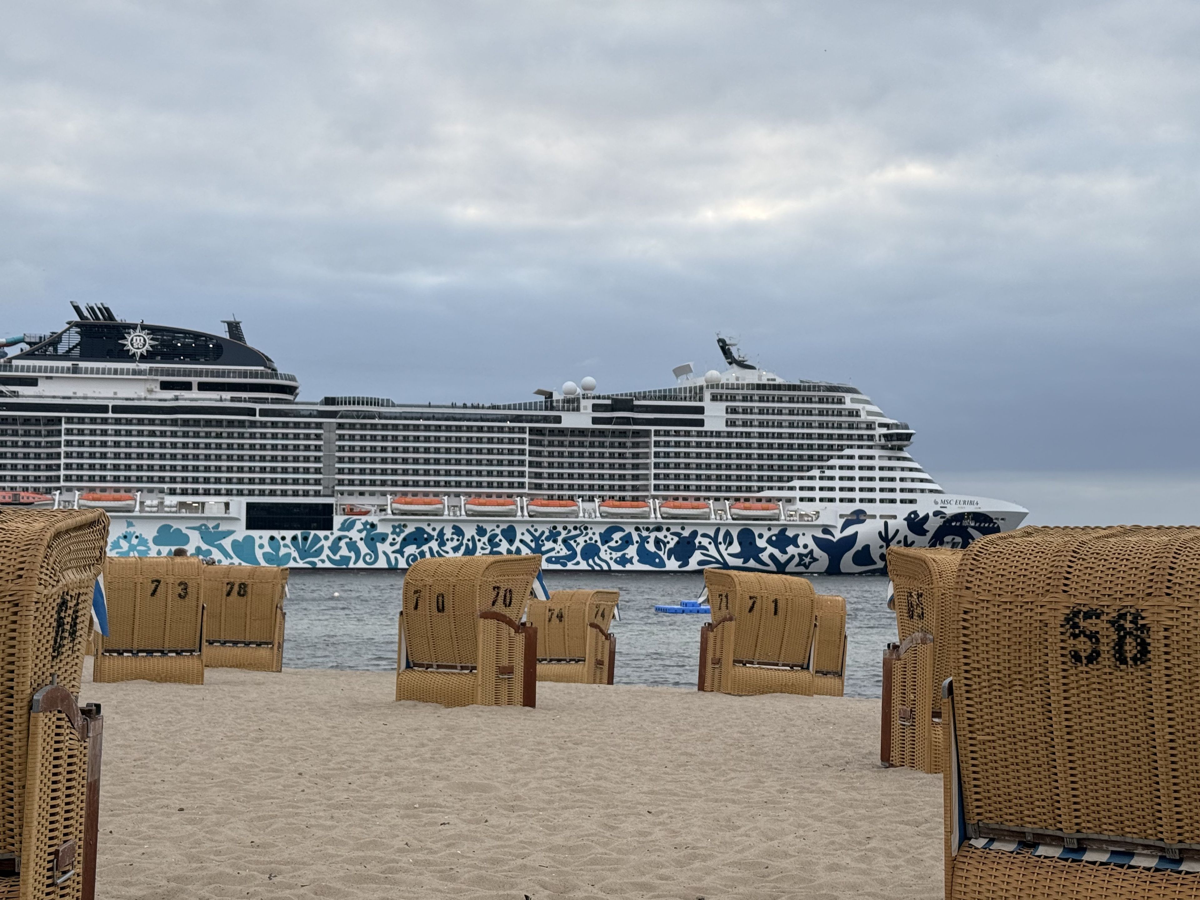 Un crucero atracado en un puerto, con sillas de playa numeradas 73, 78, 70, 74 y 58.
