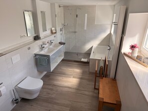 Ein modernes Badezimmer mit Toilette, Waschbecken, Dusche und Badewanne.