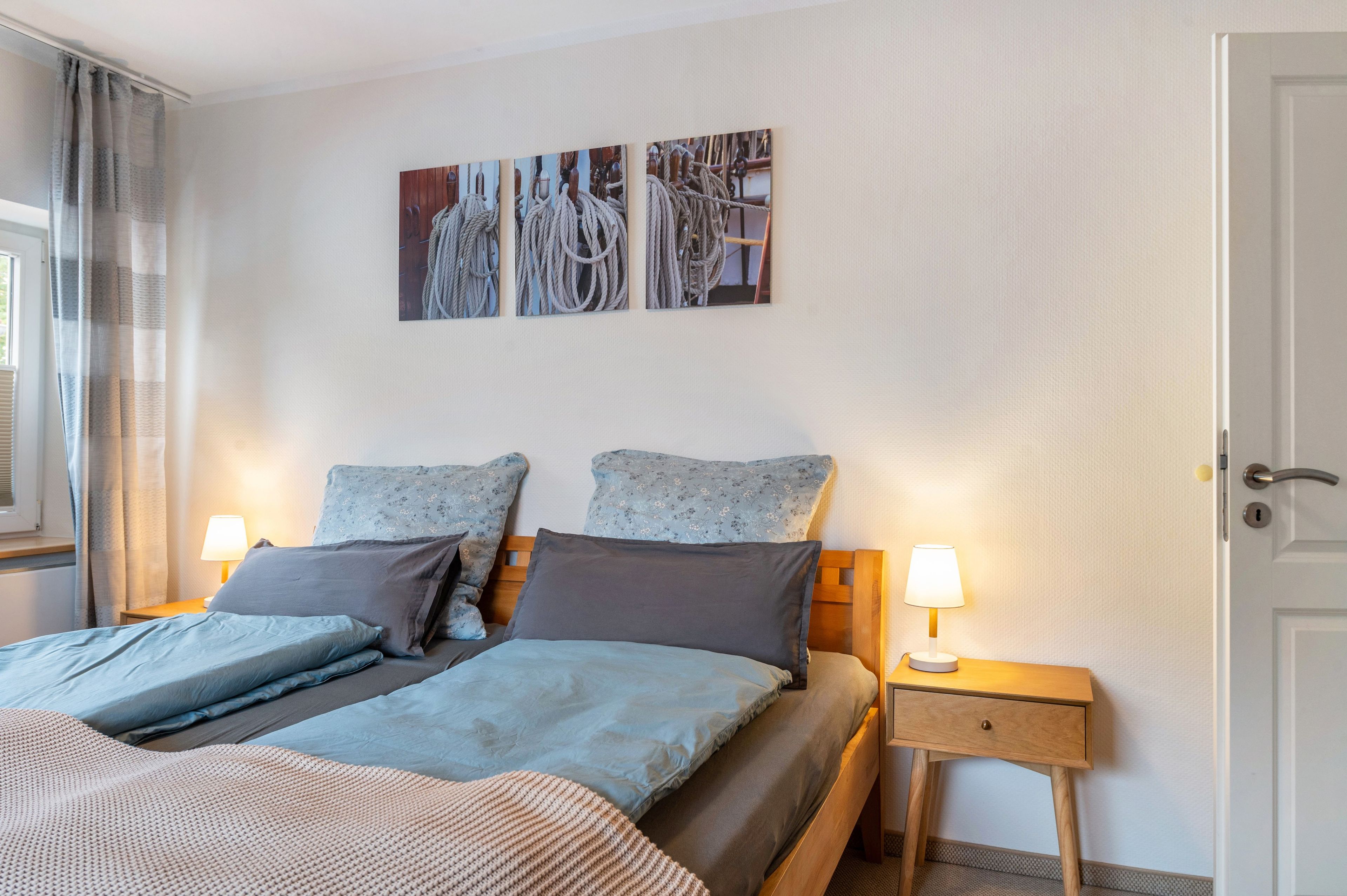 Een keurig opgemaakt slaapkamer met een bed, twee nachtkastjes en een kunstwerk aan de muur.