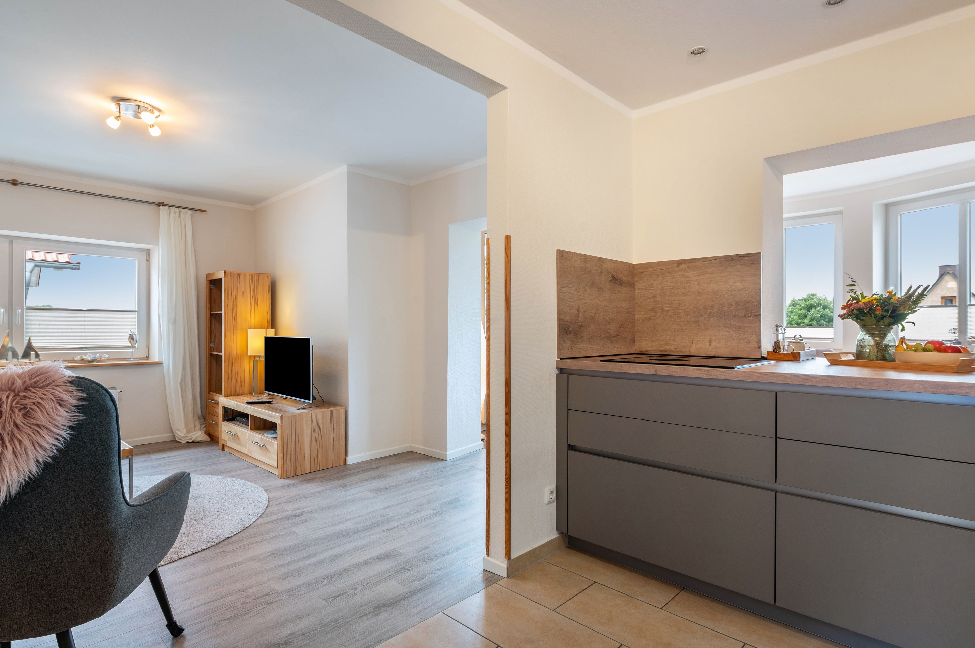 Een moderne keuken met grijze kastjes, een houten aanrechtblad en een inbouwfornuis.
