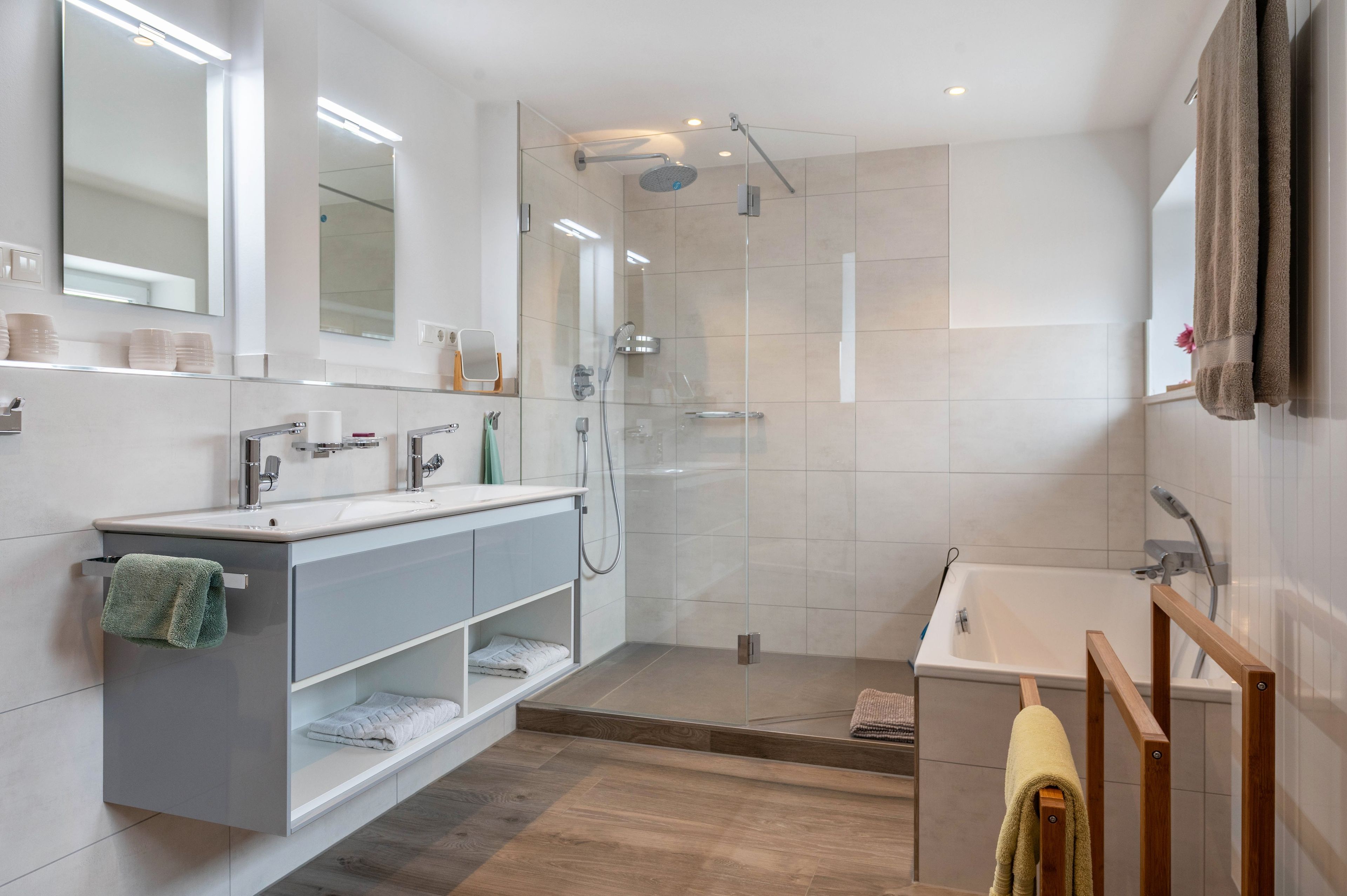Ein modernes Badezimmer mit einer Duschkabine, einem Waschtisch mit Spiegel und einer Badewanne.
