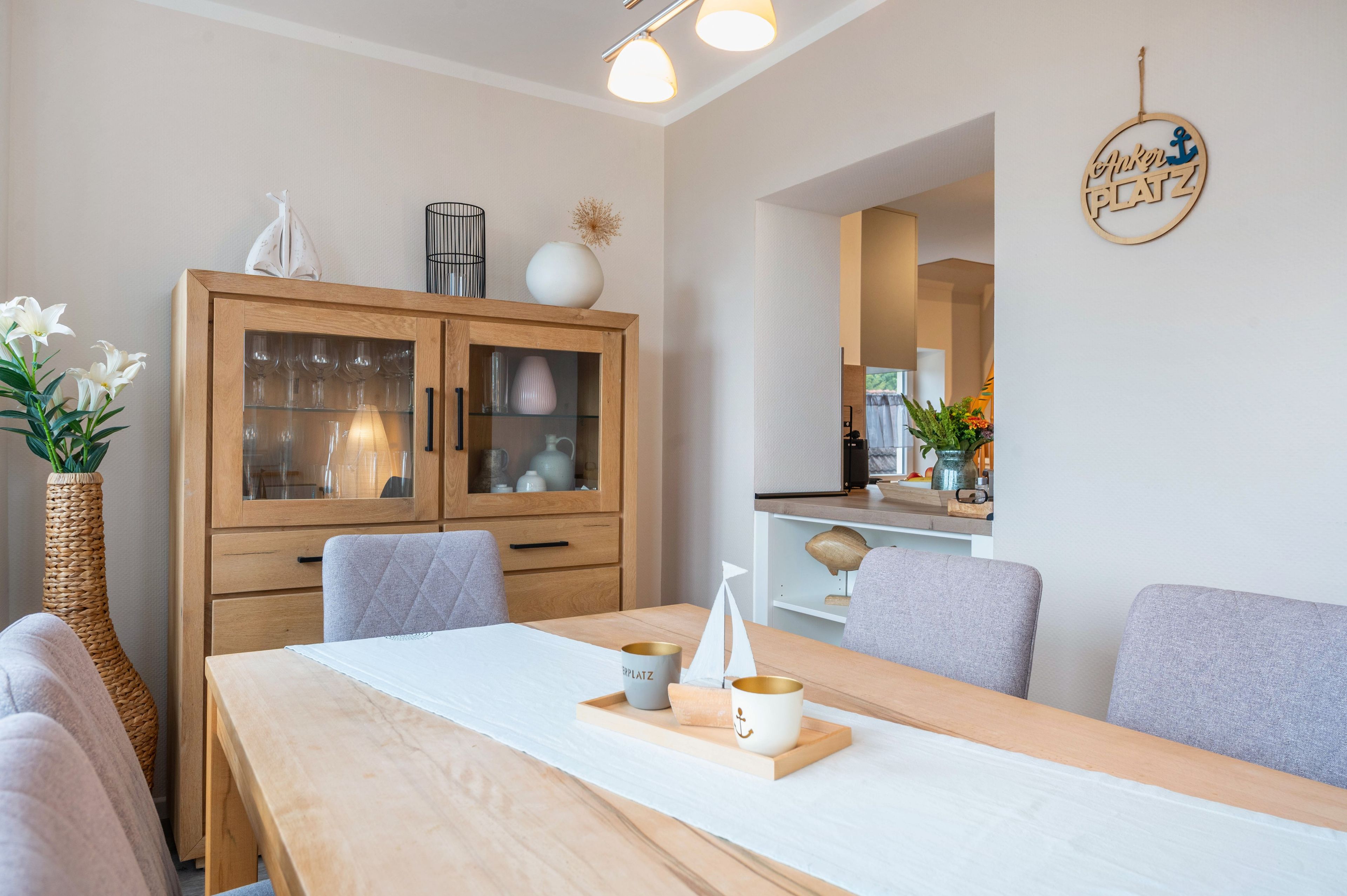 Un'area pranzo moderna con un tavolo in legno, sedie e un armadietto con ante in vetro.