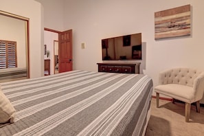 Ein Schlafzimmer mit einem großen Bett, einem Schminktisch, einem Sessel und einem Bild an der Wand.