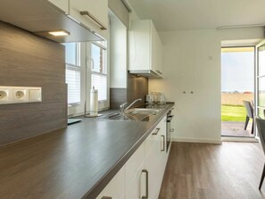 A modern kitchen with a dark countertop, white cabinets, and a view of the outdoors. - Ground Floor on the Left in the Everschop House (St. Peter-Ording)