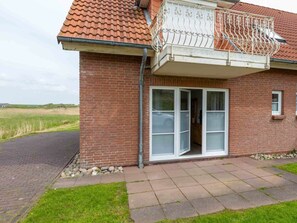 A brick house with a tiled roof, a balcony with metal railings, and a sliding glass door. - Ground Floor on the Left in the Everschop House (St. Peter-Ording)