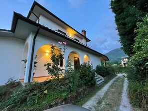 Ein zweistöckiges Haus mit weißer Fassade, gewölbten Fenstern und einem Weg zum Eingang.