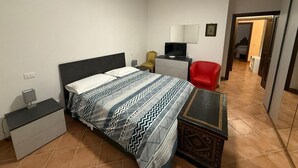 A bedroom with a bed, bedside table, chair, and a desk with a chair. - Villa 'Lori' with Mountain View, Wi-Fi and Air Conditioning (Fornaci di Barga)