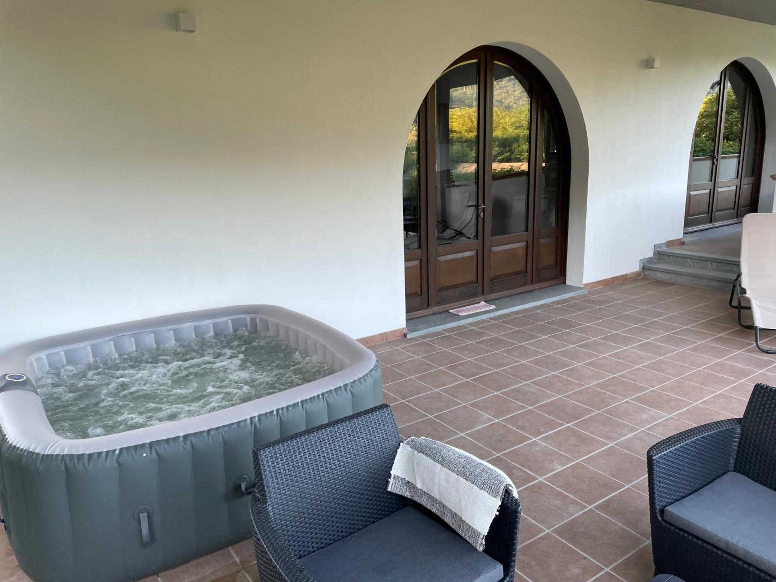 Una vasca idromassaggio con un patio piastrellato, due sedie in vimini e un'uscita coperta.