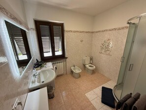 Ein Badezimmer mit Waschbecken, Bidet, Toilette und einer Duschkabine aus Glas.