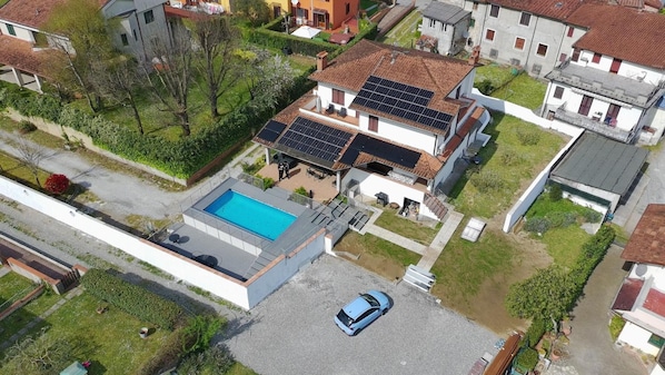 Ein Wohnhaus mit Swimmingpool, Solaranlage und einem Auto auf der Auffahrt.