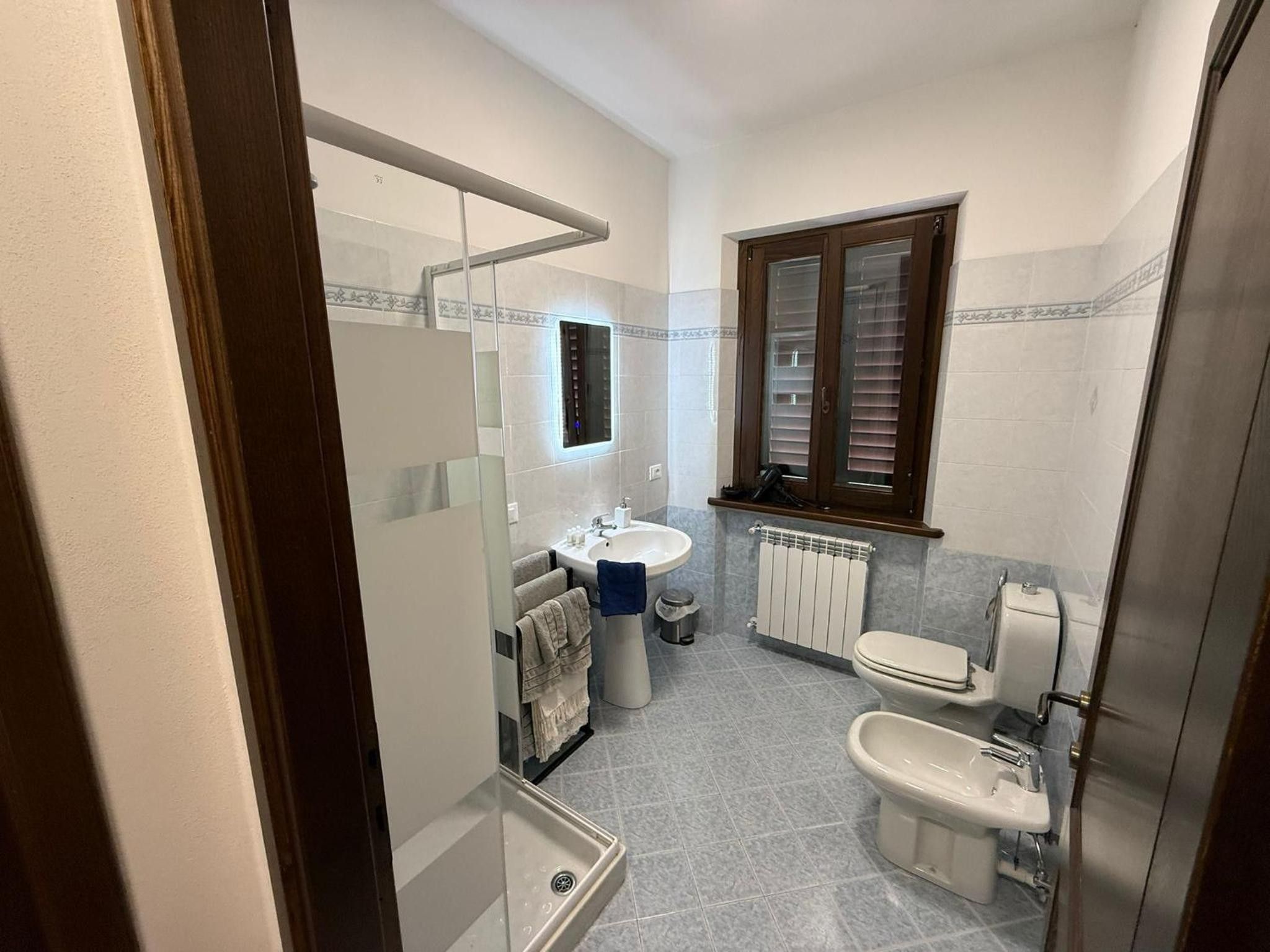 Un bagno compatto con lavandino, WC, bidet e specchio.