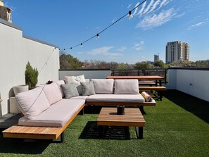 Eine Dachterrasse mit Ecksofa, Holztisch und Lichterkette.