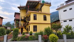 A multi-story yellow building with a balcony and a staircase. - 2-bedroom house with Free Bus Stand Pick-Up & Drop-Off (Chamba)