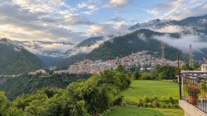 A mountainous town with a dense cluster of buildings, a grassy foreground, and a clear sky. - 2-bedroom house with Free Bus Stand Pick-Up & Drop-Off (Chamba)
