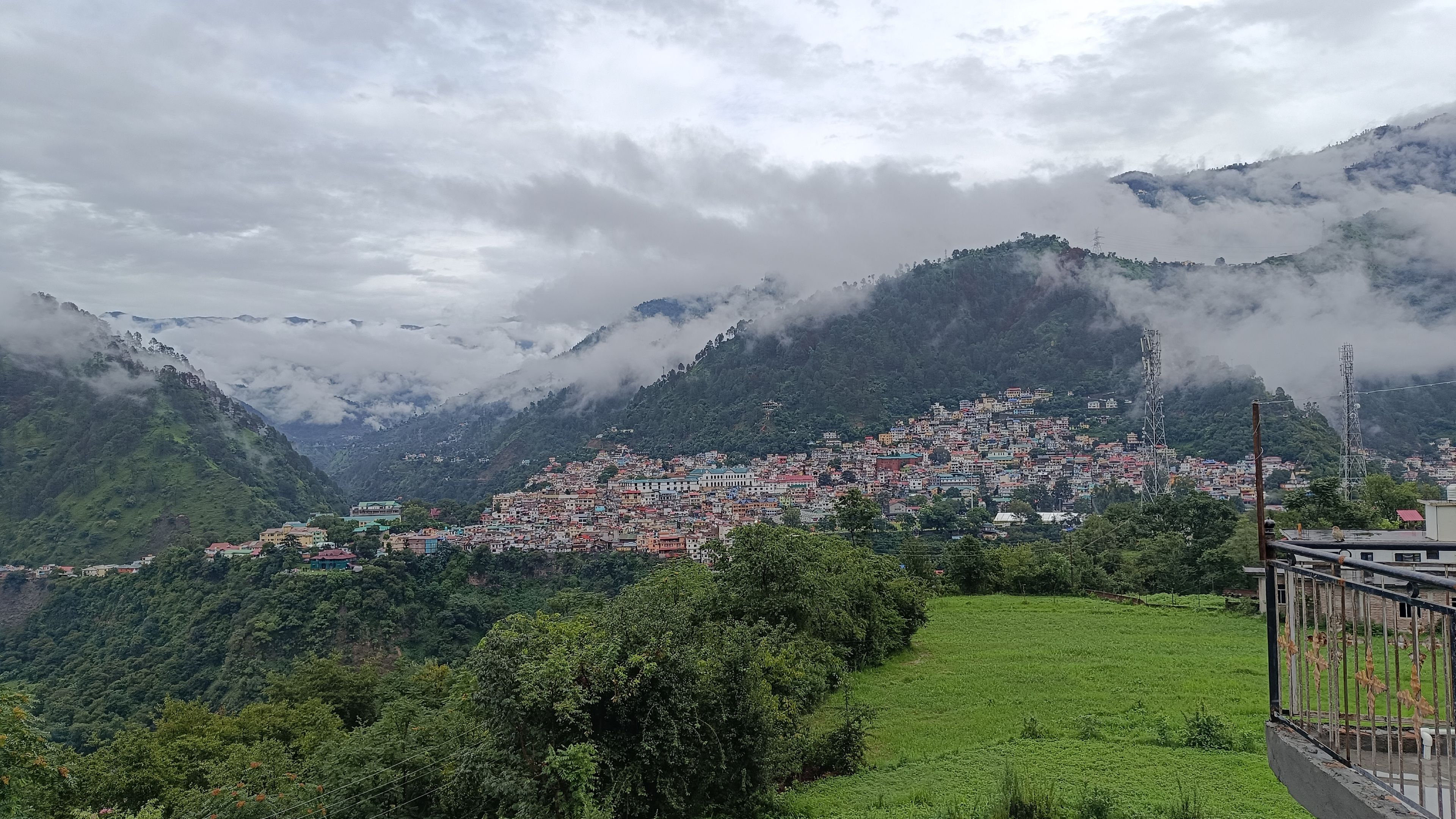 A mountainous town with buildings nestled among lush greenery and clouds.