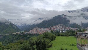 A mountainous town with buildings nestled among lush greenery and clouds. - 2-bedroom house with Free Bus Stand Pick-Up & Drop-Off (Chamba)