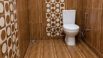 A bathroom with a toilet, shower, and wooden wall tiles.