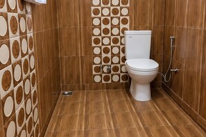 A bathroom with a toilet, shower, and wooden wall tiles. - 2-bedroom house with Free Bus Stand Pick-Up & Drop-Off (Chamba)